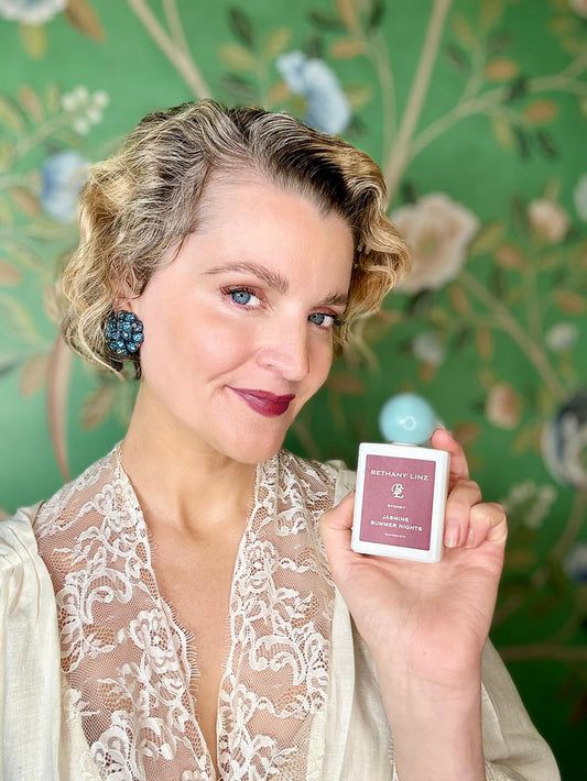 Bethany holding a bottom of Perfume with a floral background